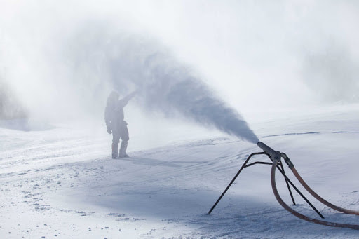 Close-up of a snow gun nozzle array atomizing water with air to form artificial snow crystals